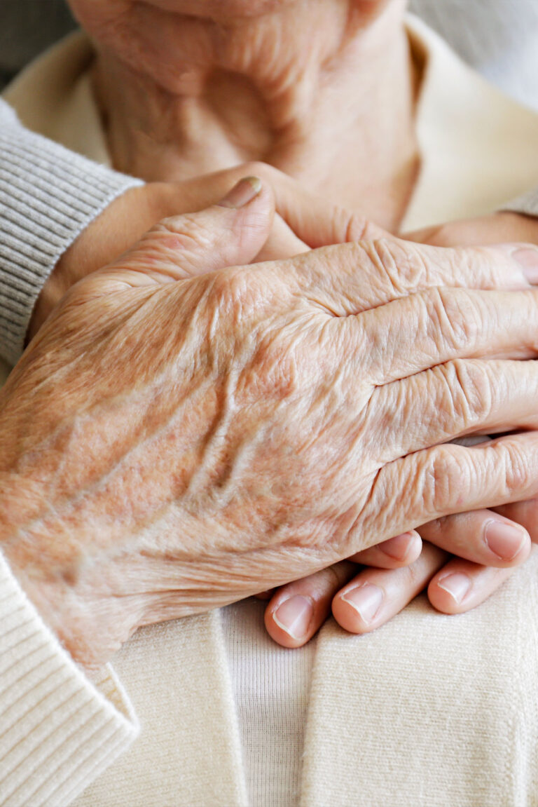 Close-up of a caregiver's hands gently holding the hands of an elderly patient, representing personalized and gentle hospice support.